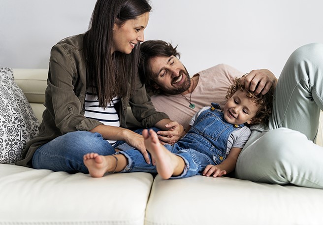 Familie entspannt auf dem Sofa Der Darmflora-Aufbau ist für Kinder sehr wichtig