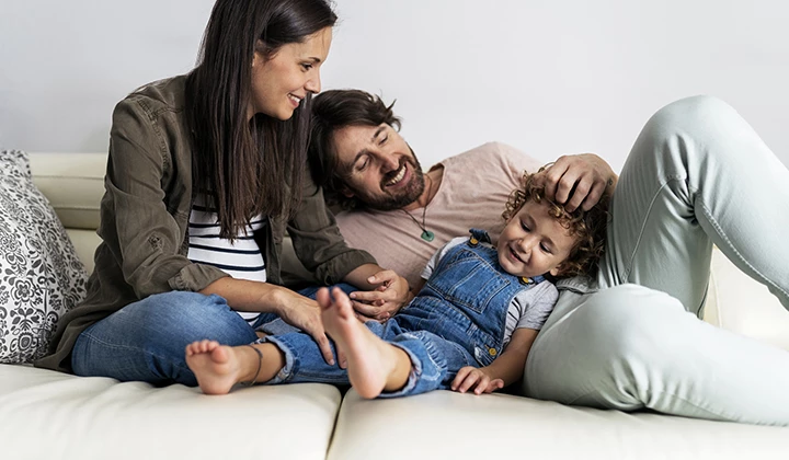 Familie entspannt auf dem Sofa Der Darmflora-Aufbau ist für Kinder sehr wichtig